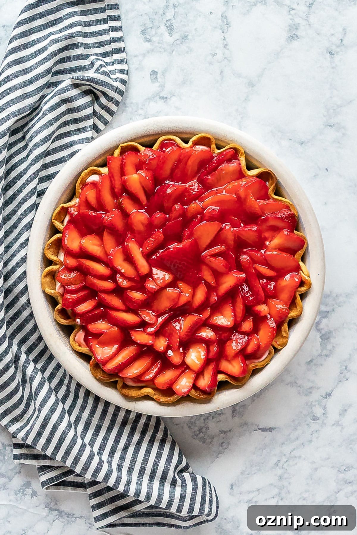 Strawberry Cream Cheese Pie Recipe with Fresh Strawberries 2 An overhead image of a strawberry cream pie with a striped napkin next to it.