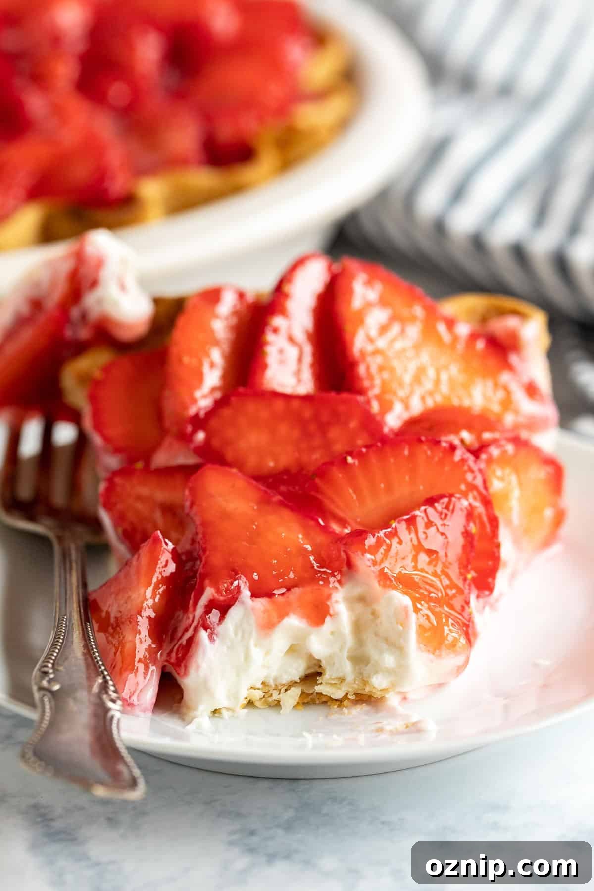 Strawberry Cream Cheese Pie Recipe with Fresh Strawberries 3 An image looking straight at a slice of strawberry cream cheese pie with a bite taken off revealing the creamy filling with the strawberries on top.
