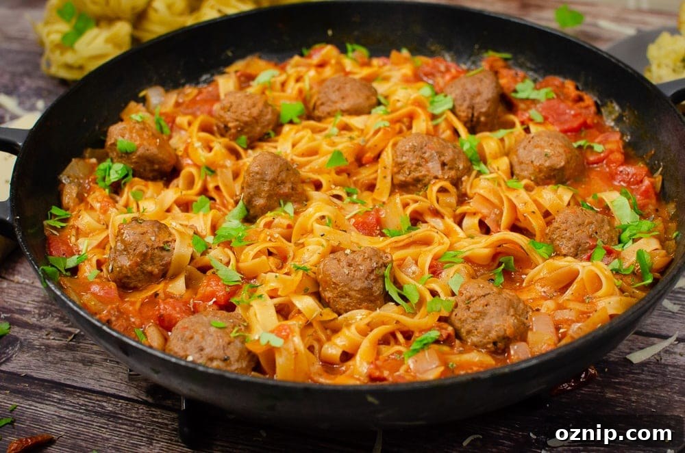 One-Pot Spicy Meatball Pasta served in a cast iron pan with sprinkled chopped parsley on top for garnish