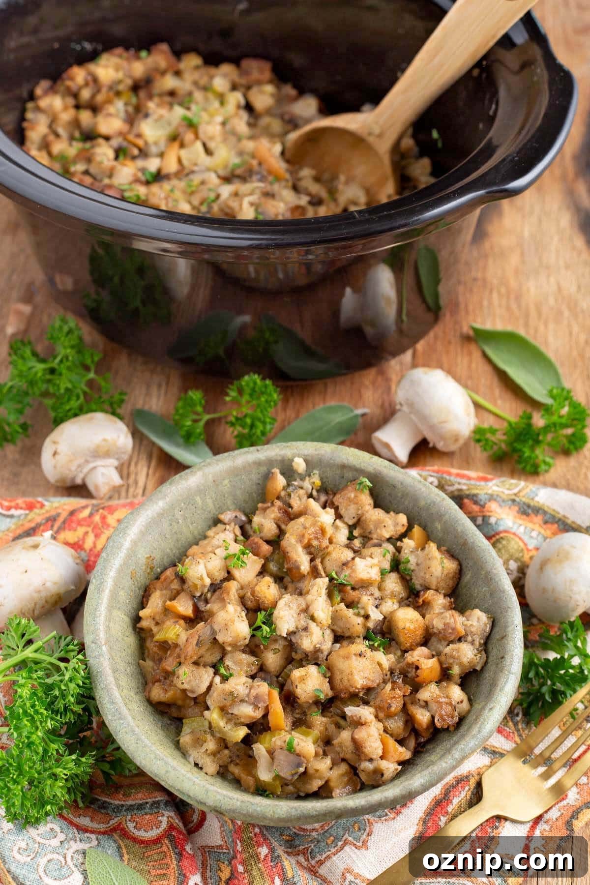 easy slow cooker stuffing in a green bowl in front of black crock with garnishes