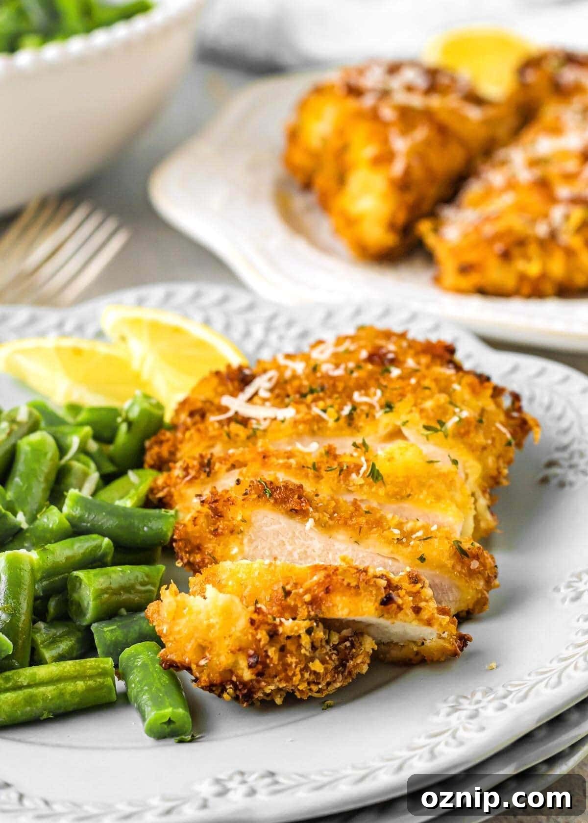 Air Fryer Parmesan Crusted Chicken Recipe 7 Air Fryer Parmesan Chicken sliced on a plate with green beans