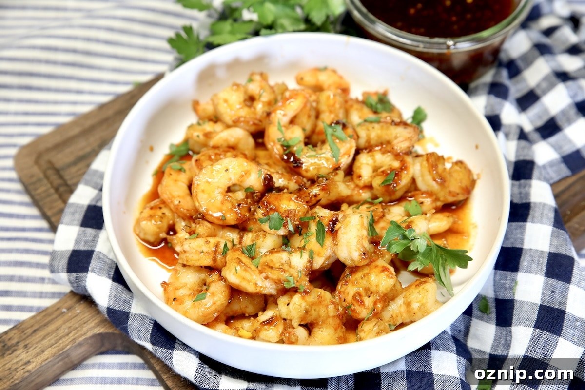 Bowl of glazed sweet and spicy shrimp on a checked towel.