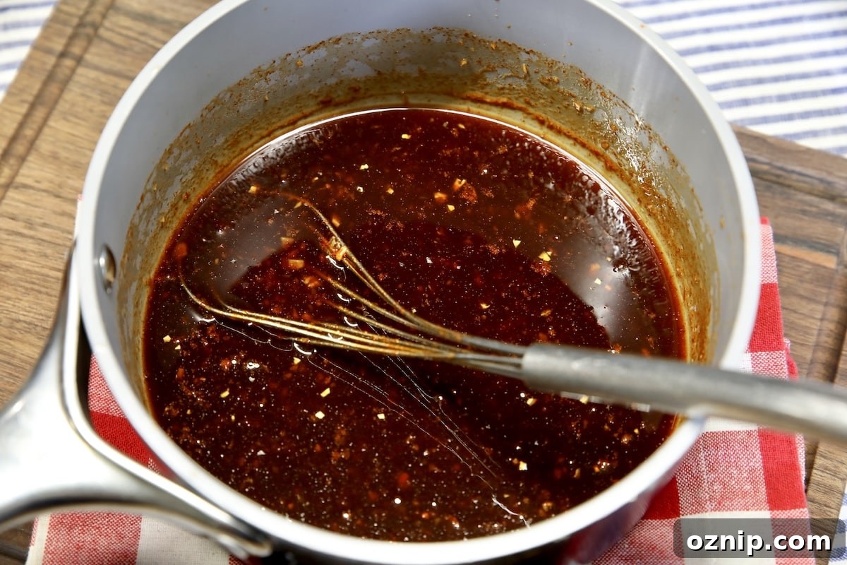 Pan of spicy maple glaze with a whisk.
