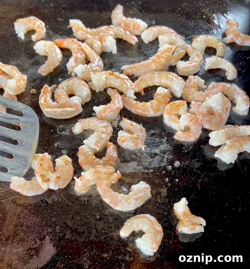 Flattop griddle cooking shrimp.
