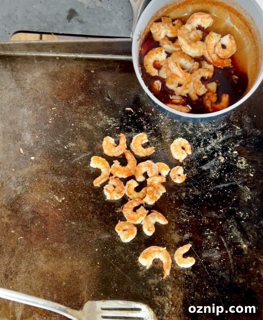 Shrimp on griddle, placing in pan of sauce.