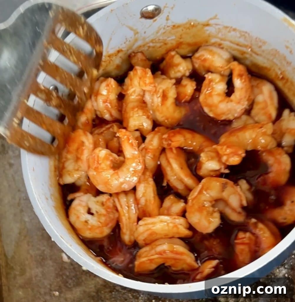 Mixing shrimp with sauce in a pan.