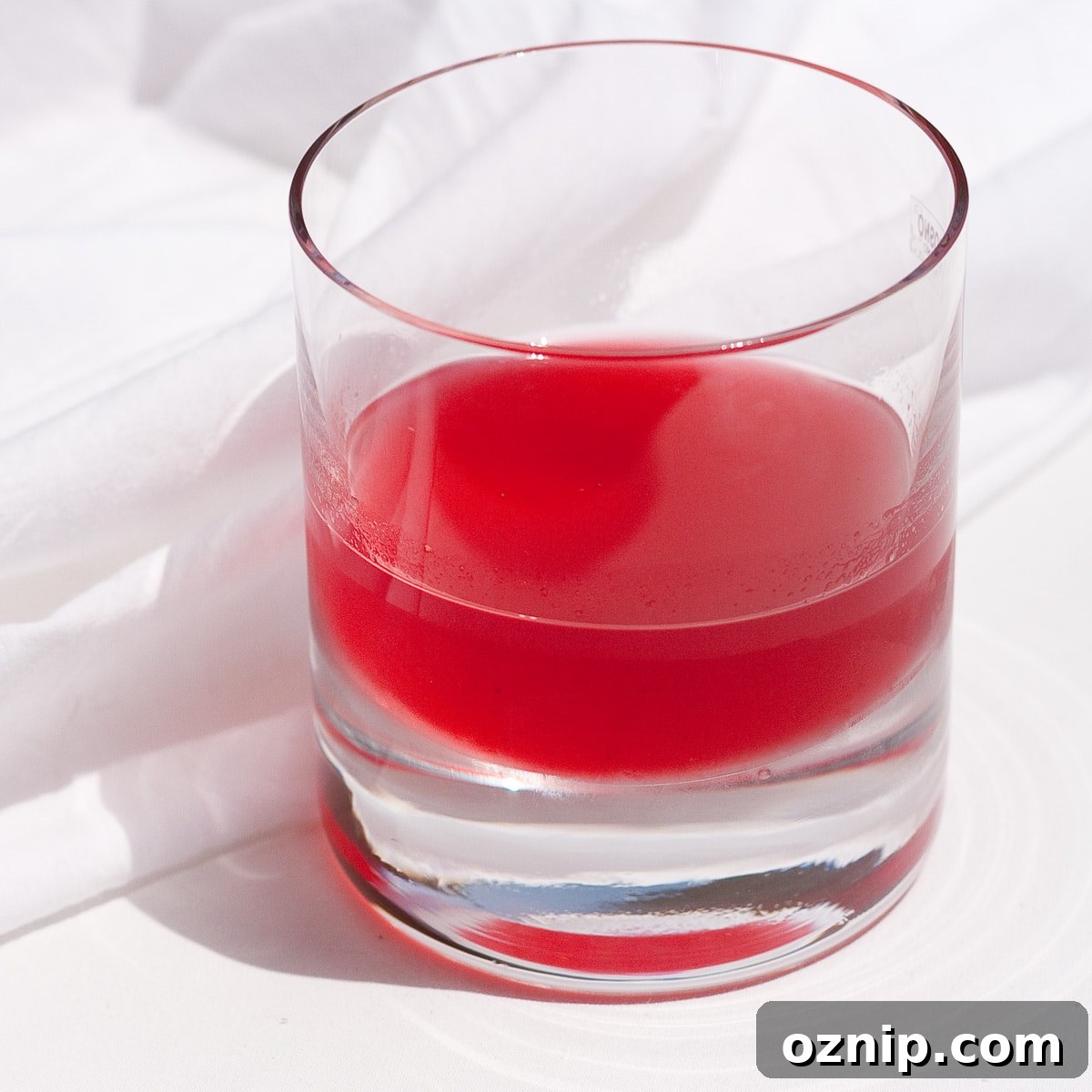 raspberry lime simple syrup in an old fashioned glass on a white background.