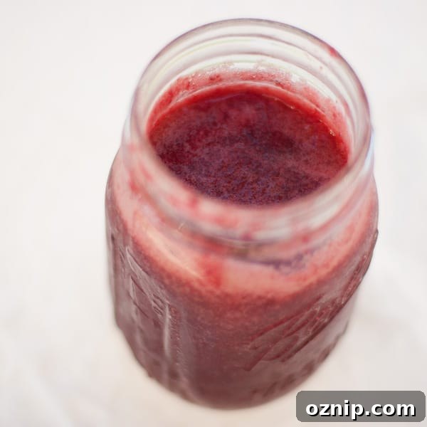 looking down into a mason jar filled with red jam.