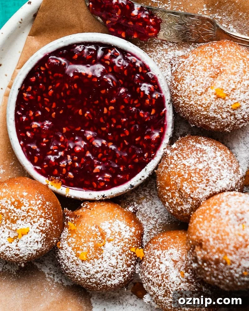 Ricotta fritters dusted with sugar and orange zest, served with berry jam.