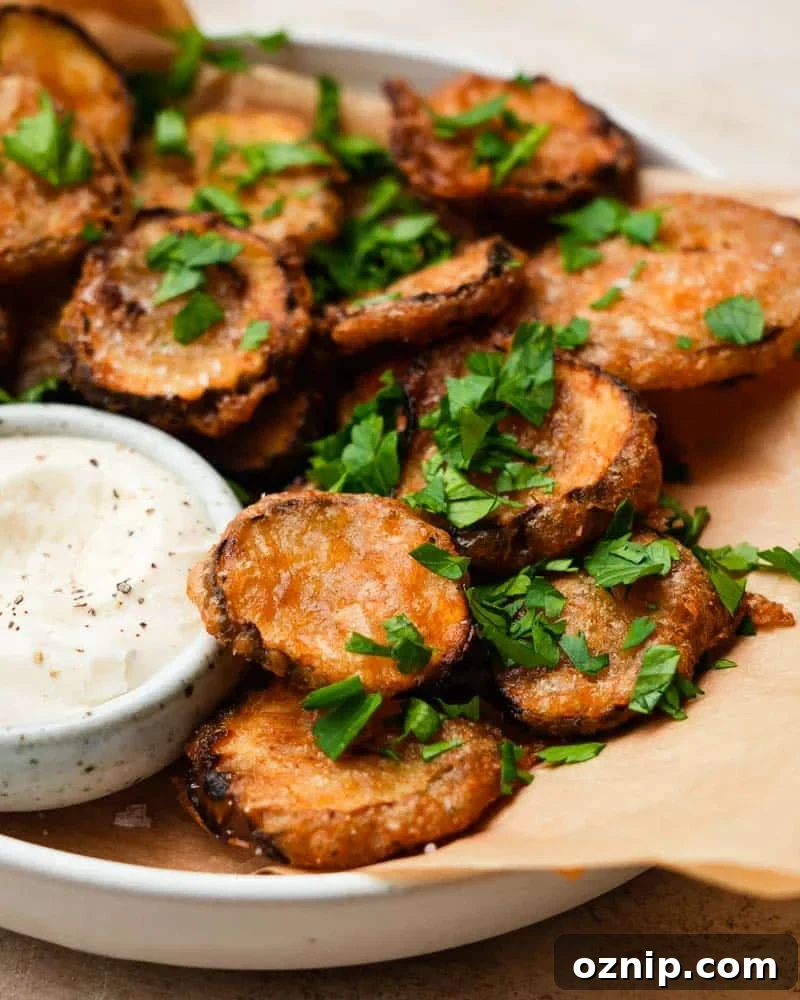 A plate of fried pickles topped with fresh herbs and a mayo dip.