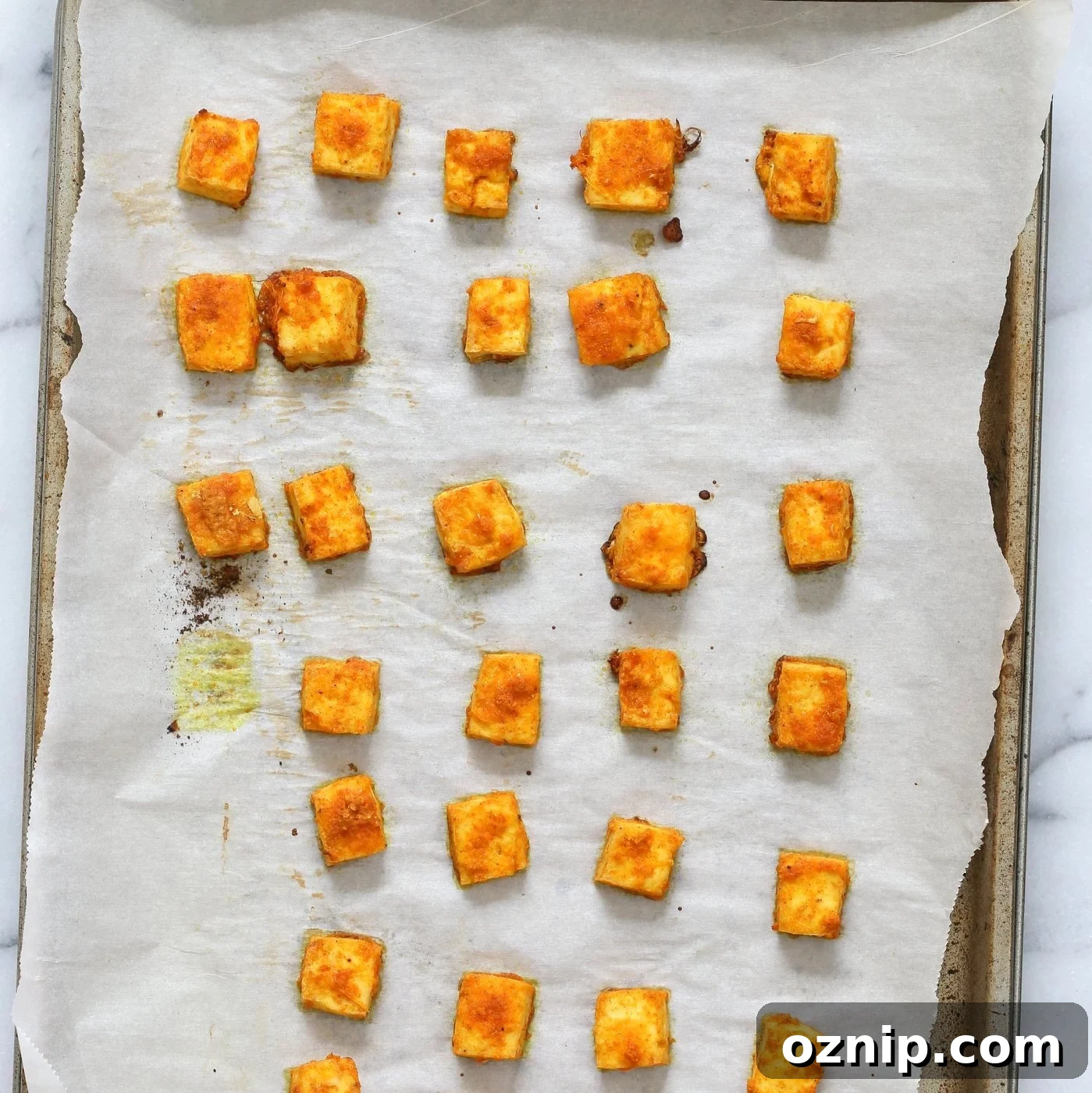 Marinated Tofu Cubes baked on Parchment lined baking sheet for Indian Butter Tofu Masala dish