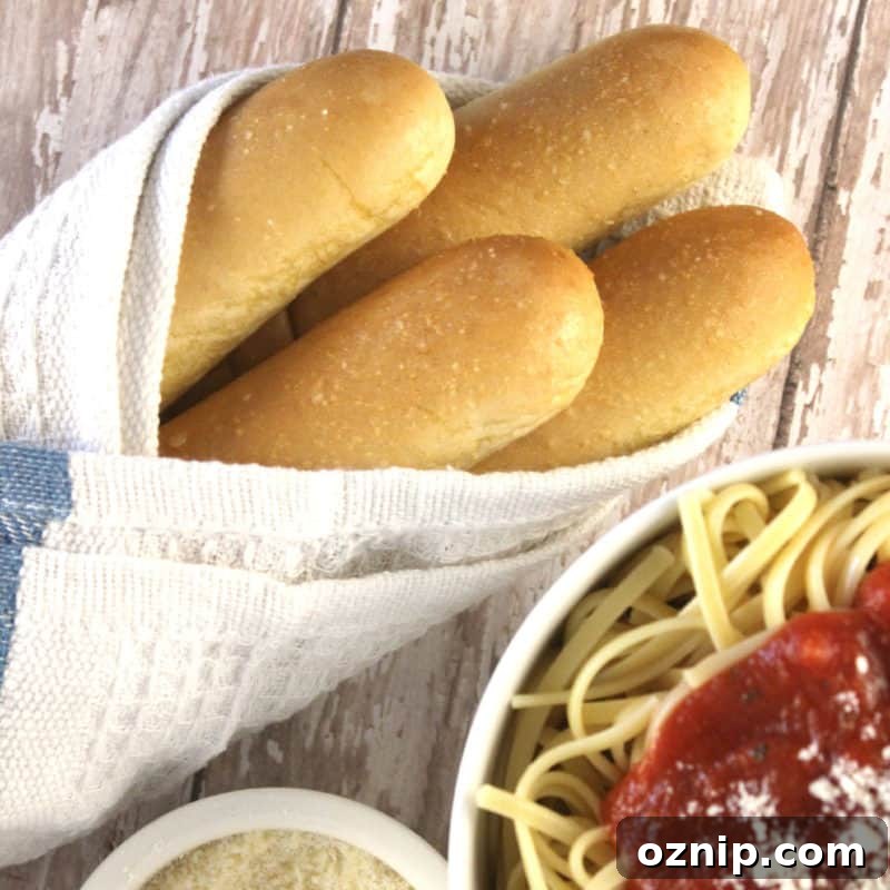30+ Side Dishes for Soup to Complete Your Meal 4 Olive Garden breadsticks wrapped in a cloth next to a bowl of spaghetti