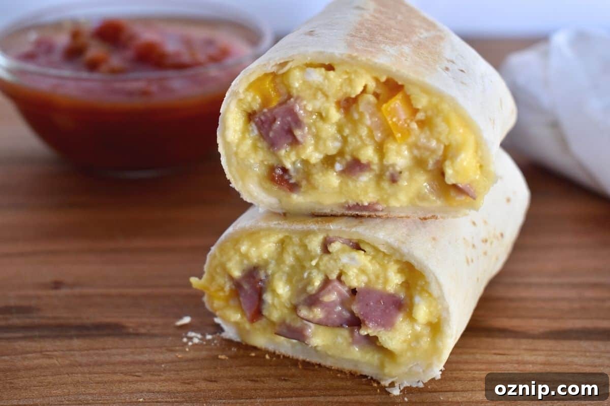 Freezer-Friendly Turkey Sausage Breakfast Burritos Recipe 6 Breakfast burrito sliced in half and stacked on each other on a wooden cutting board.