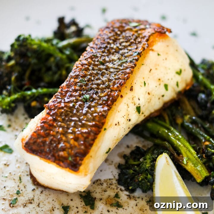 Buttery lemon chilean sea bass with crispy skin on a plate with sautéed broccolini.