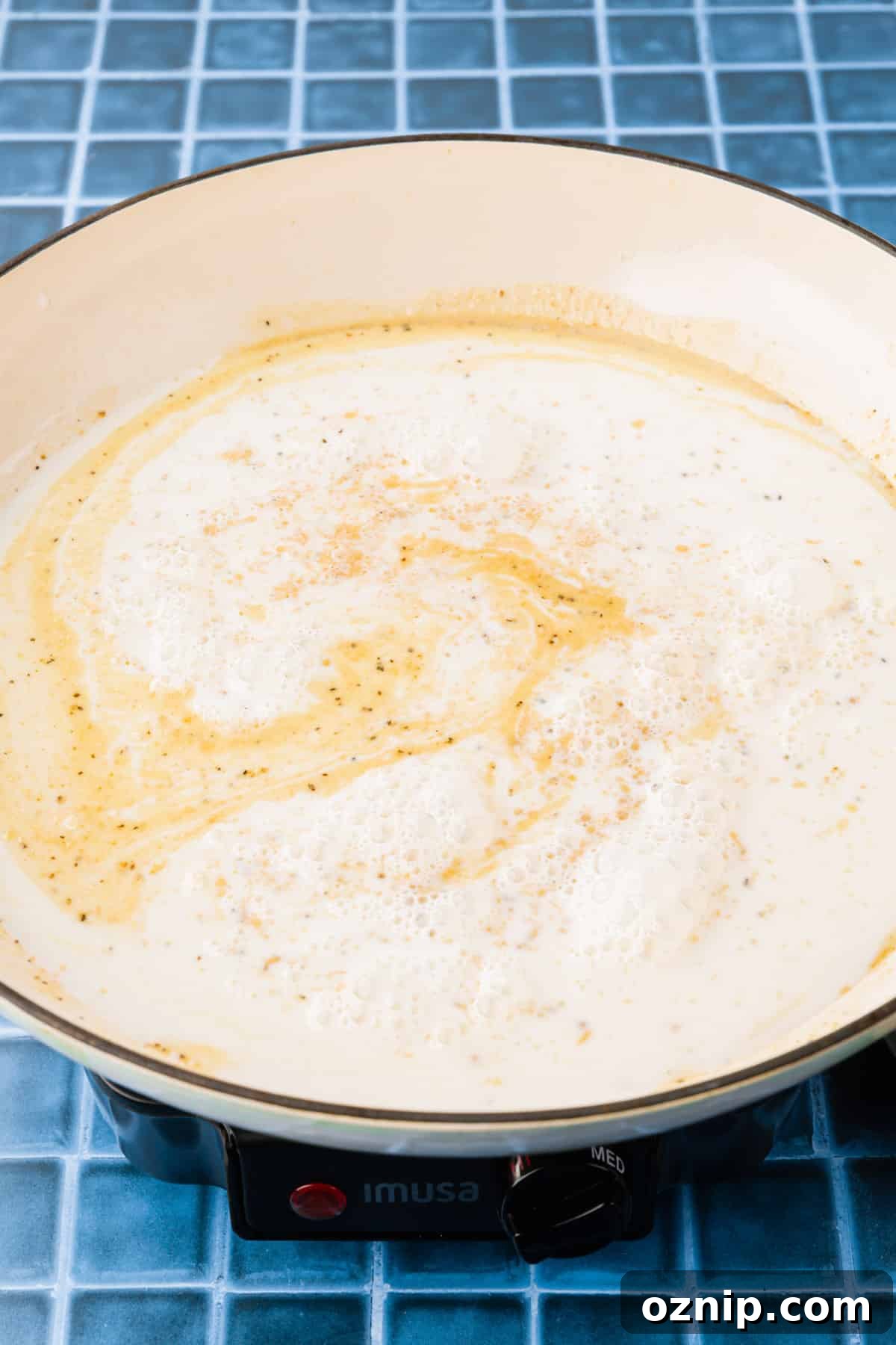 Creamy Gluten Free Mac and Cheese Recipe 7 A white braising pan with a milk and gluten free roux to make a creamy sauce.