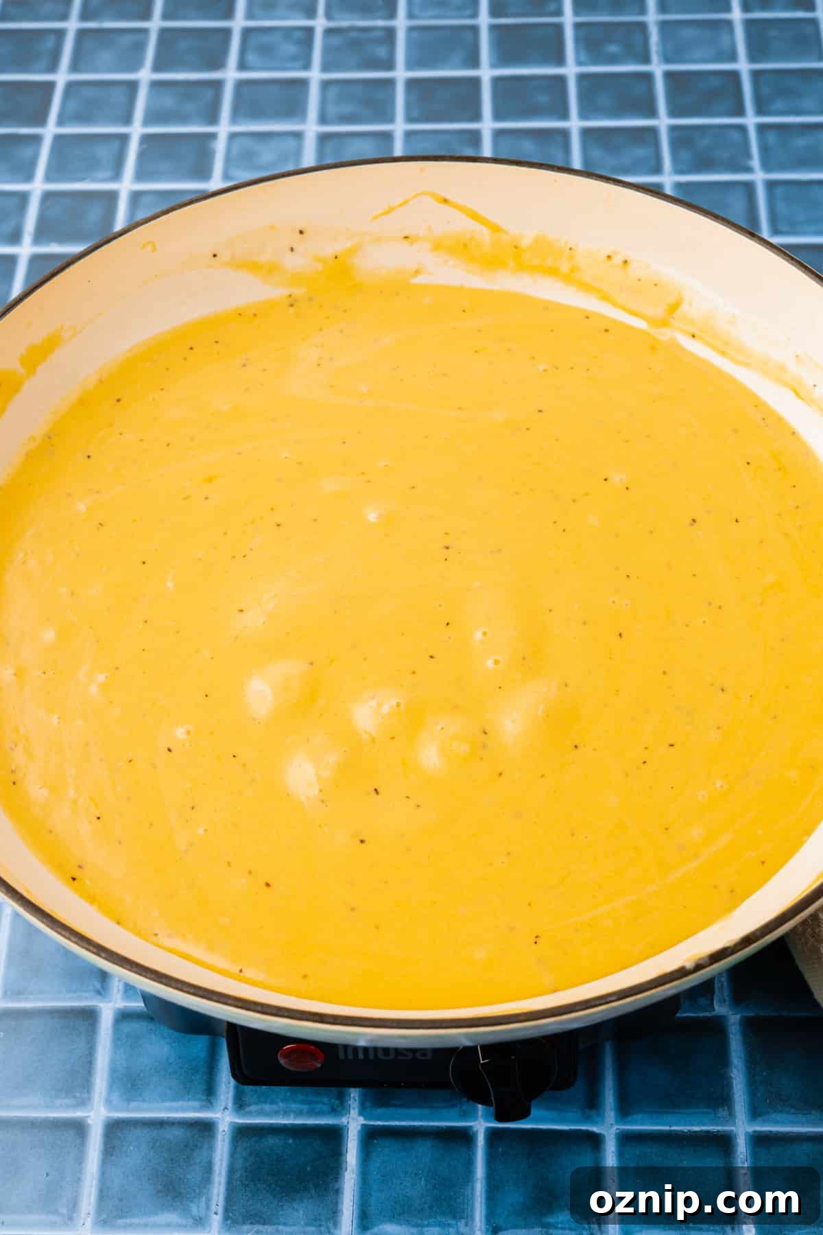 Creamy Gluten Free Mac and Cheese Recipe 9 A white braising pan with a gluten-free cheese sauce in it.