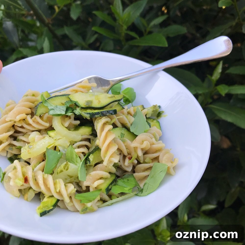 white bowl filled with wholegrain pasta tossed together with garlicky chilli spiked greens.