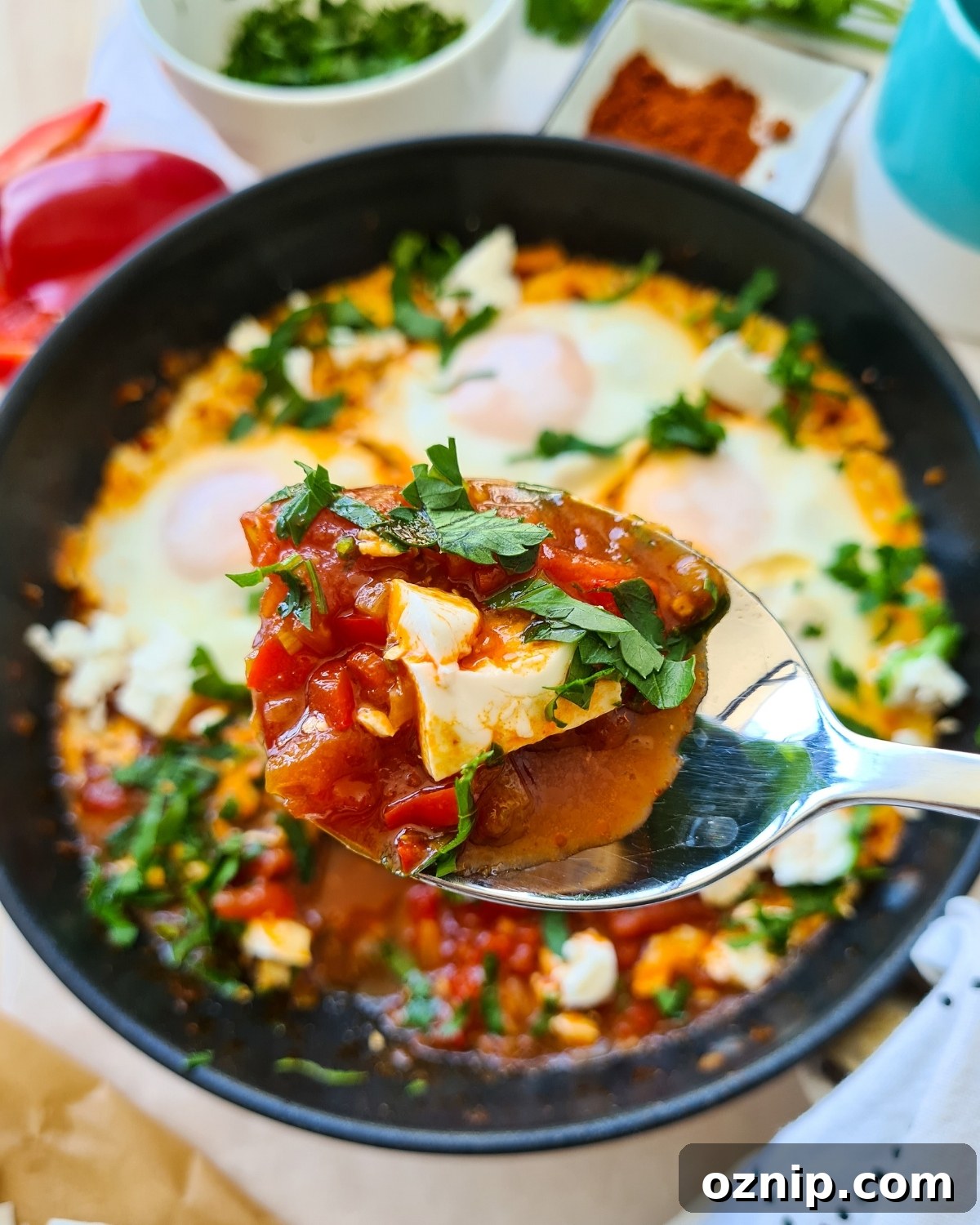 Feta Shakshuka Recipe with Poached Eggs 13 Close up spoonful of shakshuka with feta with entire pan in background