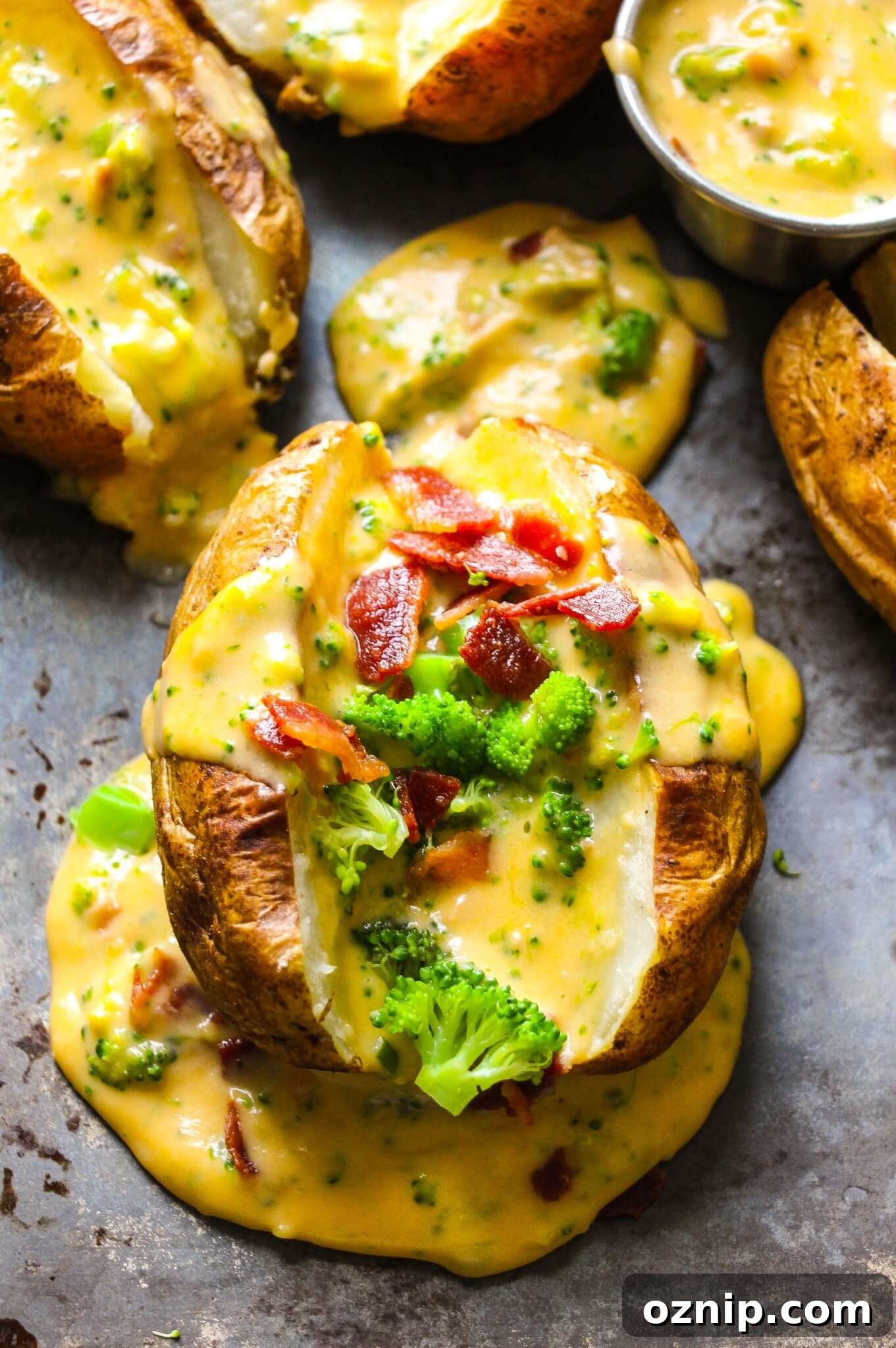 a photo of a baked potato sliced in half, open, and stuffed with broccoli, bacon crumbles and topped with homemade cheese sauce.