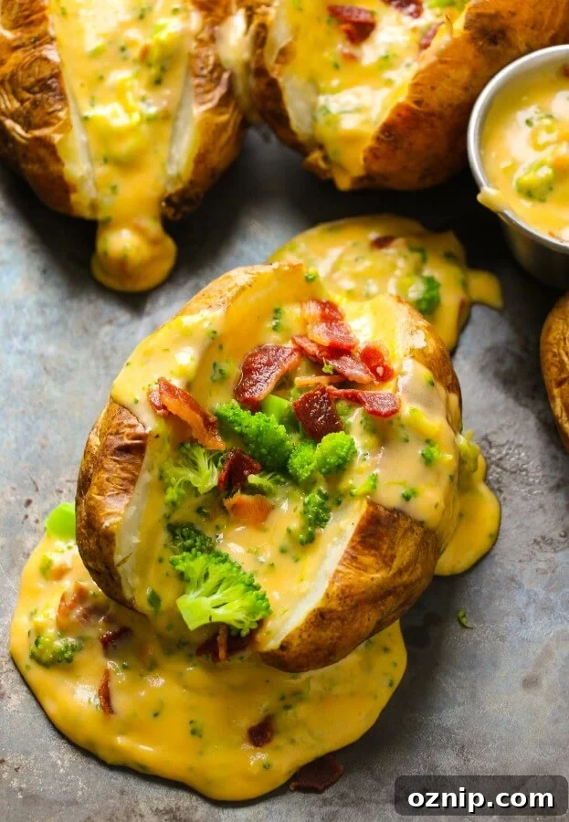a photo taken over the top of a baked potato that has been sliced in half and loaded with steamed broccoli, crumbed bacon and homemade cheese sauce.