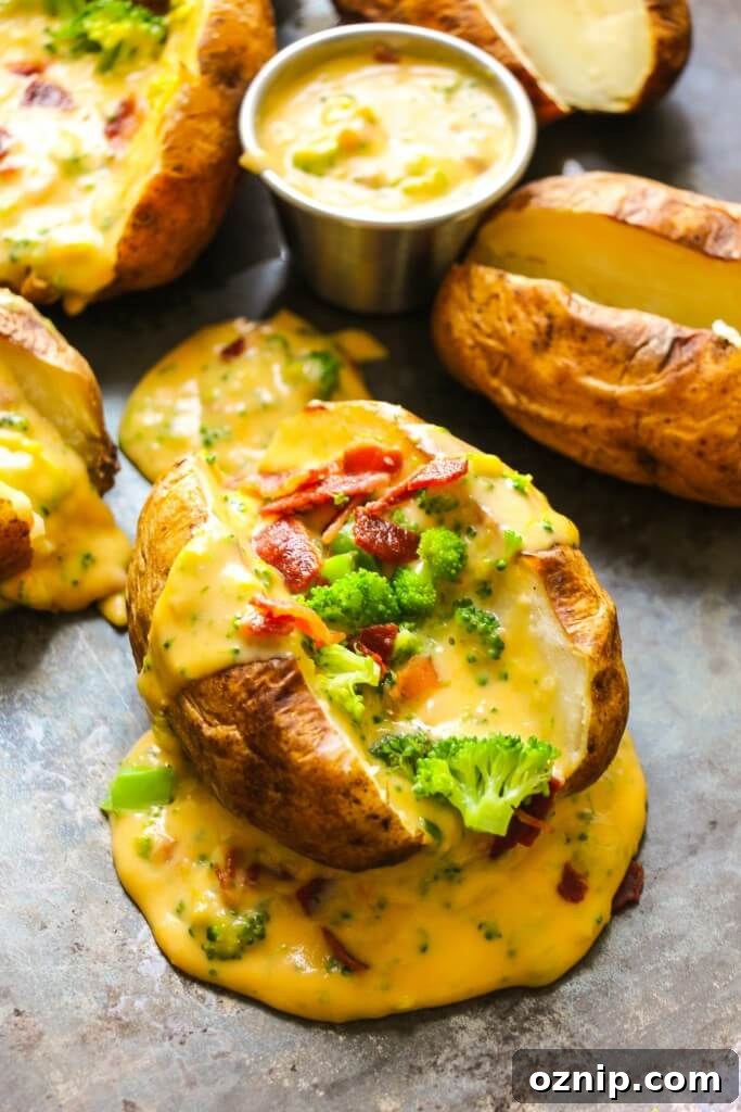a photo of a baked potato sliced open and topped with creamy cheese sauce, broccoli and bacon crumbles.