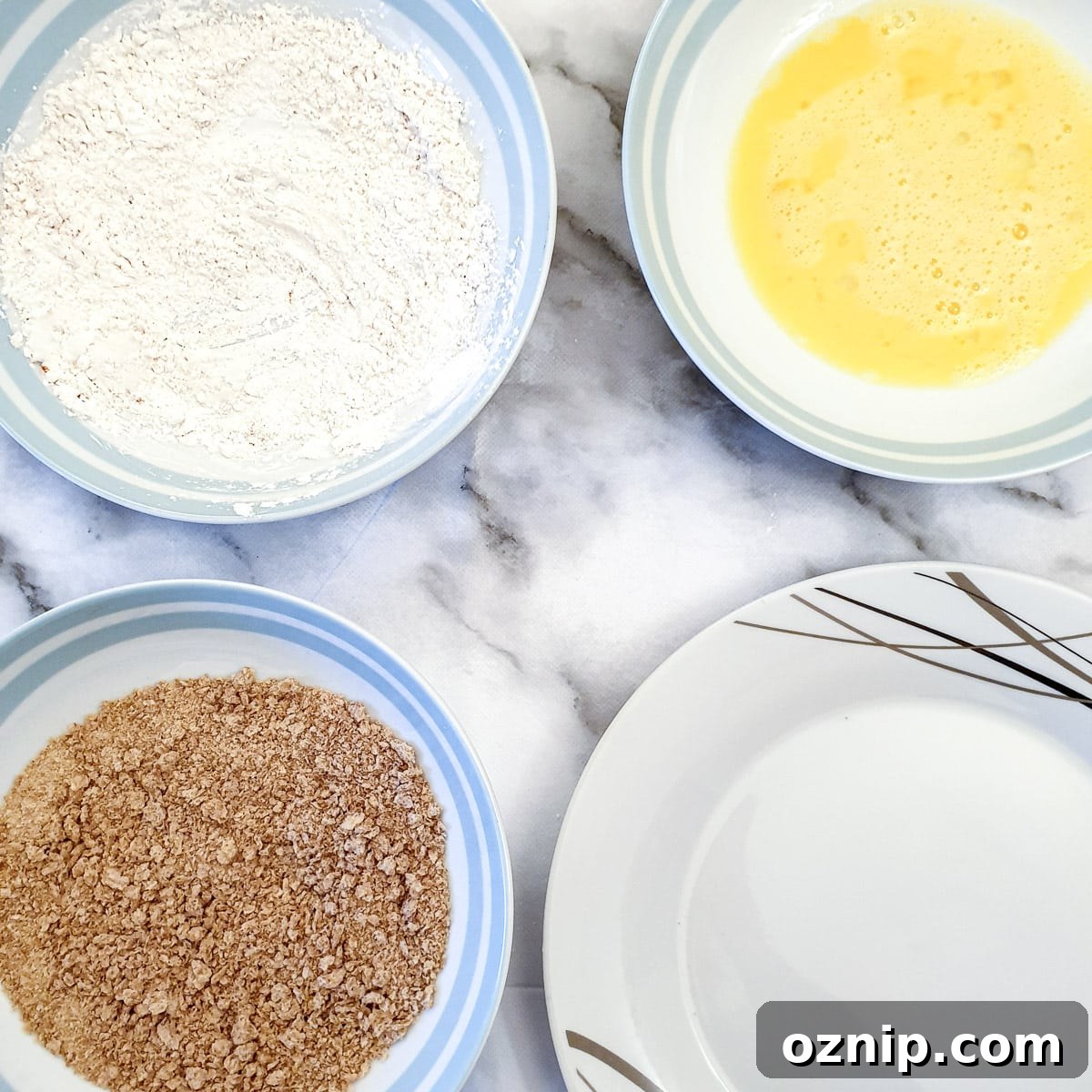Dishes of flour, egg and breadcrumbs ready for coating the schnitzels.