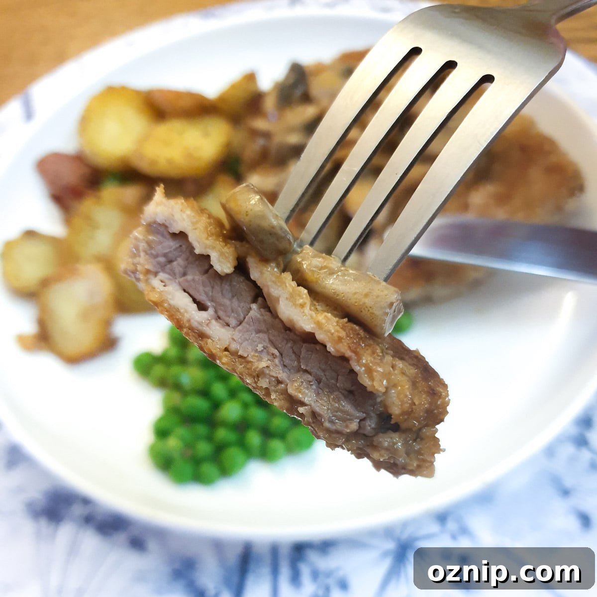 Close up of a piece of crumbed beef schnitzel on a fork.