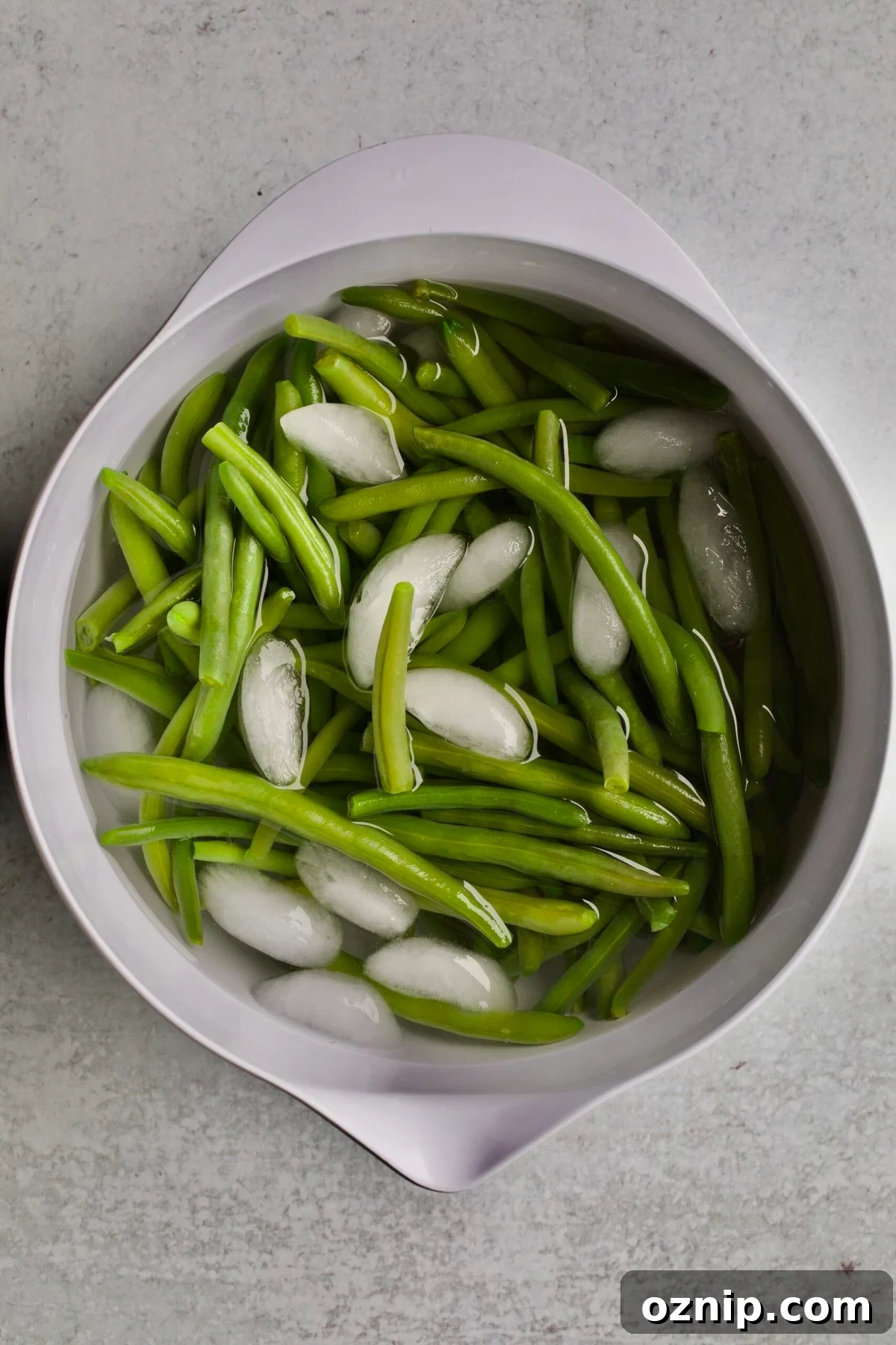 process of making sautéed green beans: placing the green beans in ice water.