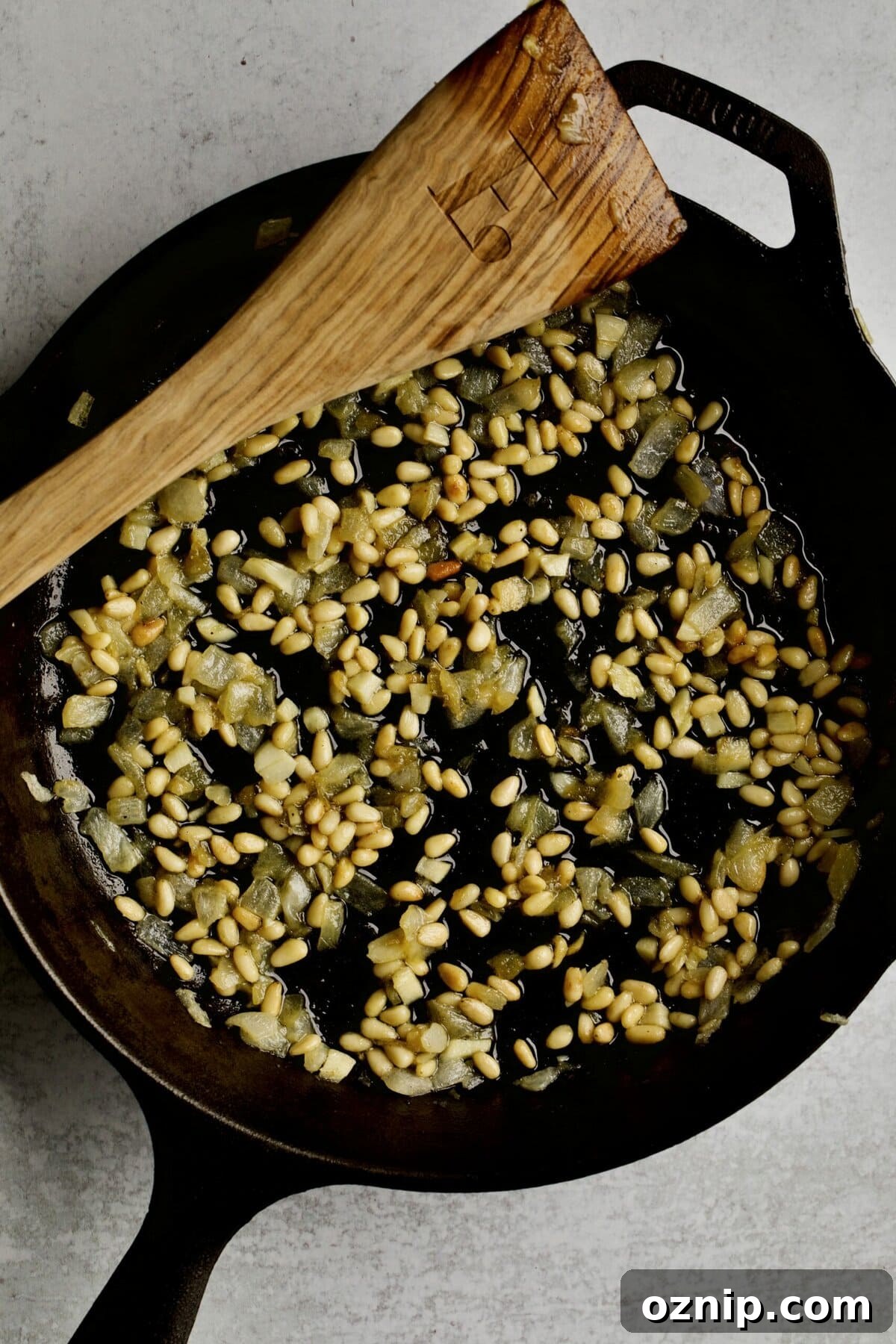 process of making sautéed green beans: frying the onions and pine nuts.