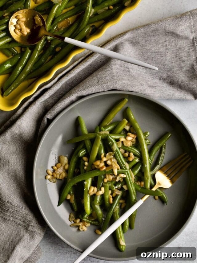 Sautéed Frozen Green Beans Recipe (Easy) on a grey plate with a fork napkin in background.