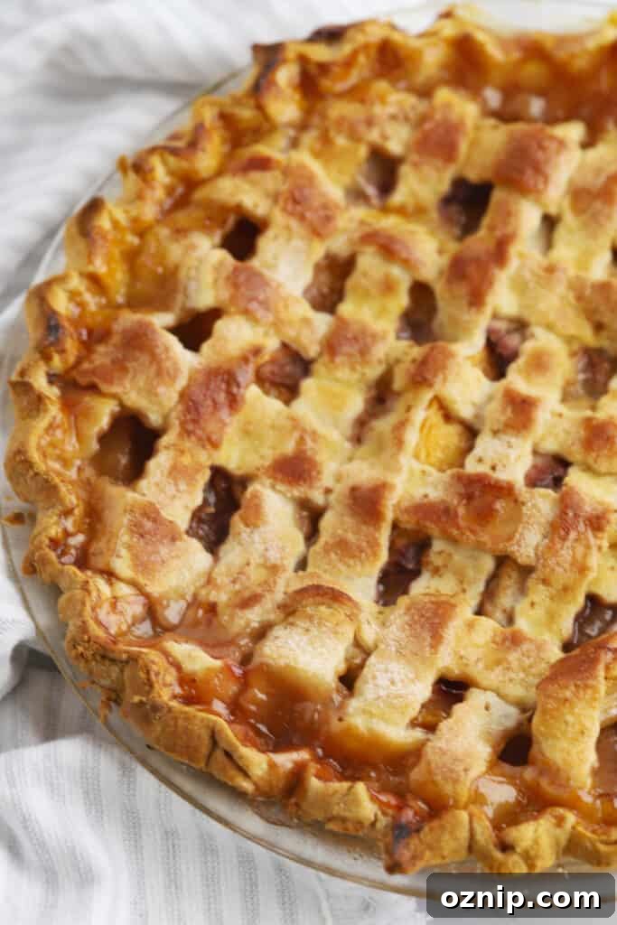 Baked Peach Pie with a Flaky Golden Crust 2 A full peach pie baked inside a pie plate with a lattice top crust.