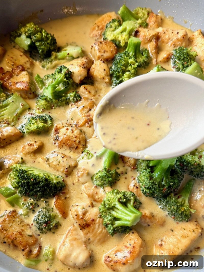 Creamy Honey Mustard Chicken with Broccoli 12 honey mustard sauce poured over the chicken and broccoli with a spoon.