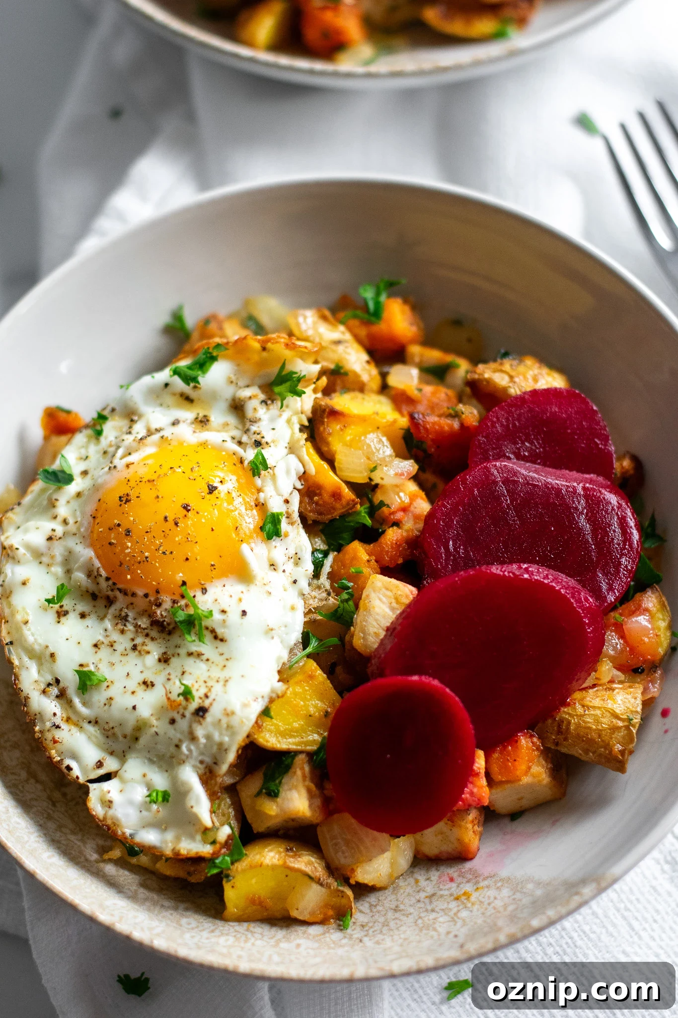 Biksemad: Traditional Danish Meat and Potato Hash Recipe 4 A bowl of veggies and meat topped with a fried egg and pickled beets.