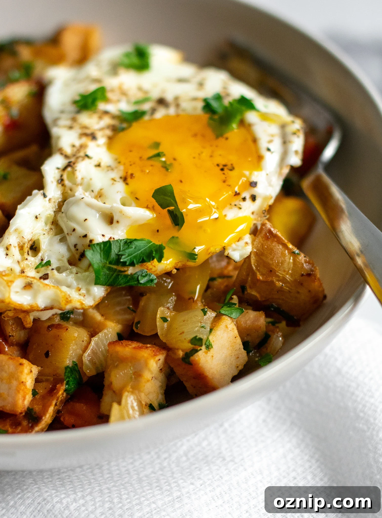 Biksemad: Traditional Danish Meat and Potato Hash Recipe 6 An egg on top of potatoes and meat in a bowl.
