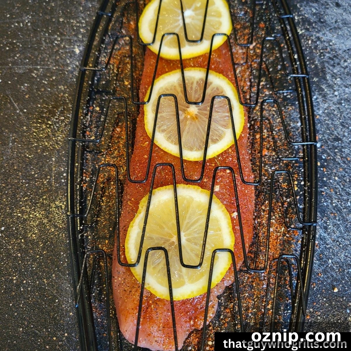 Salmon fillet seasoned with lemon slices in fish basket before grilling