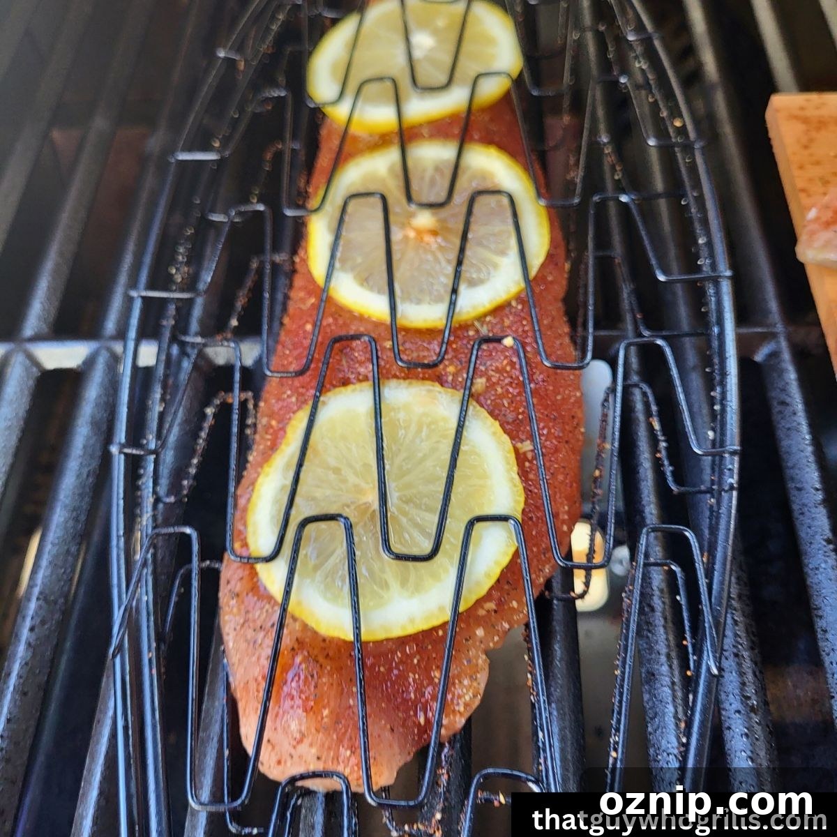 Seasoned salmon fillet in fish basket with lemon slices