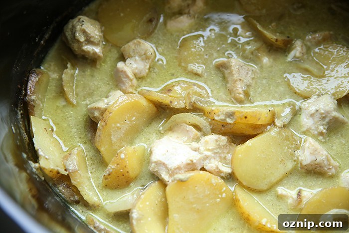 A crockpot full of green curry chicken and potatoes.