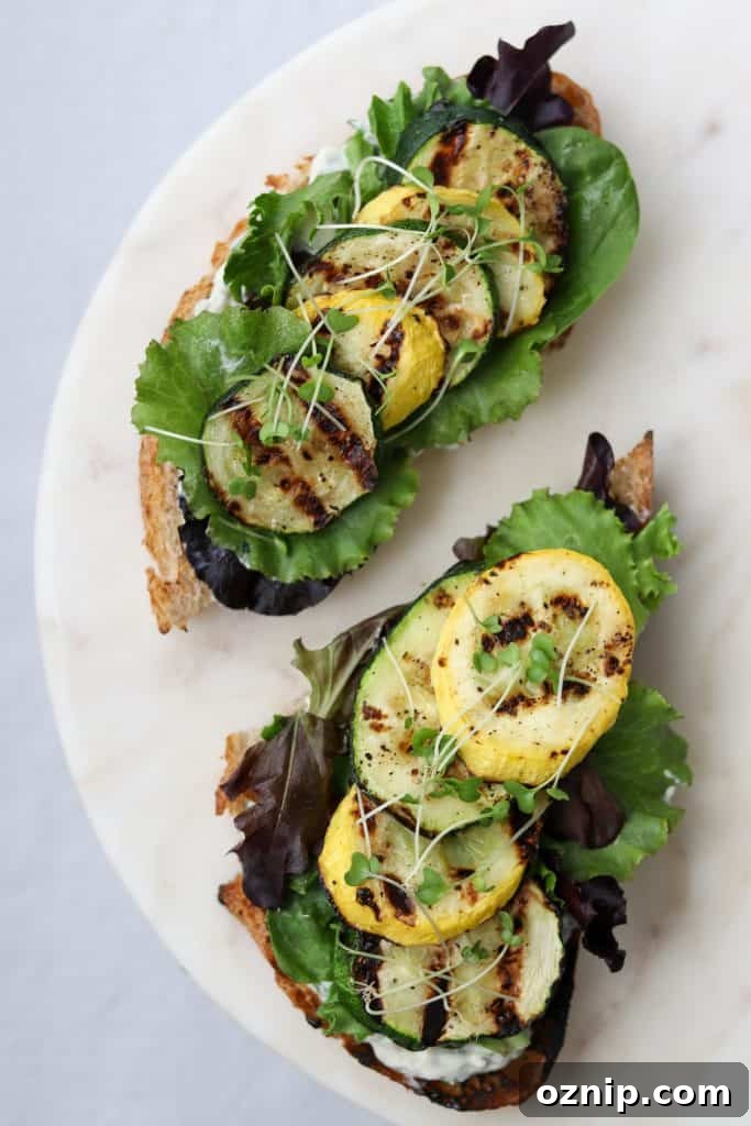 Open sandwiches topped with lettuce and grilled summer squash on a plate