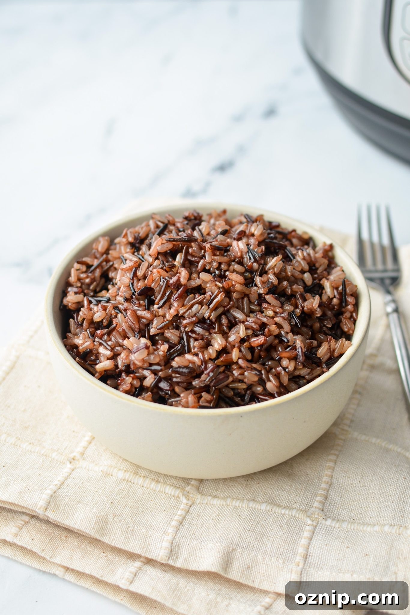 A bowl of rice on an off white napkin.