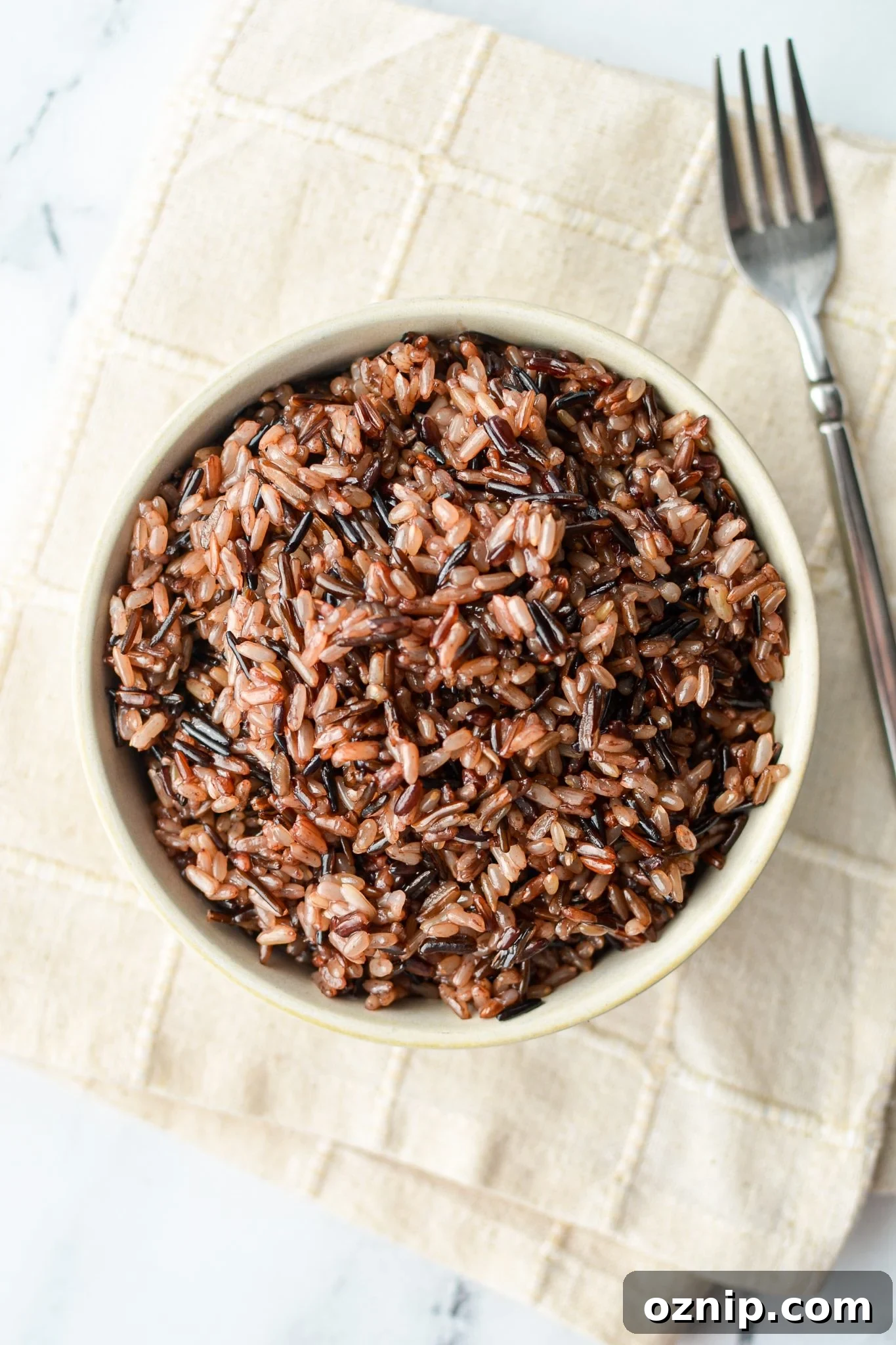 A bowl of wild rice on an off white cloth.
