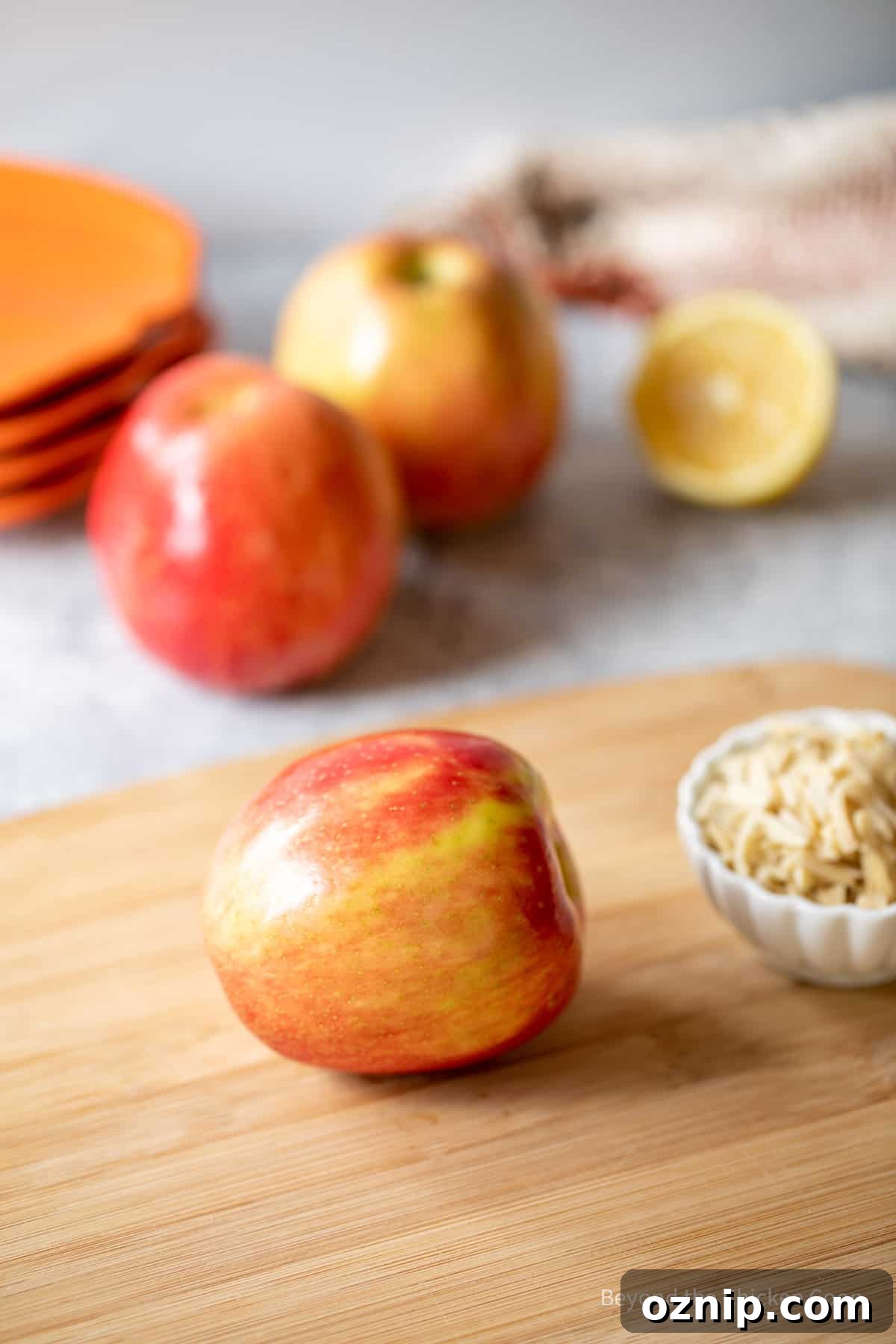 How to Make Apple Teeth for Halloween 3 A apple on a cutting board next to a bowl of slivered almonds.
