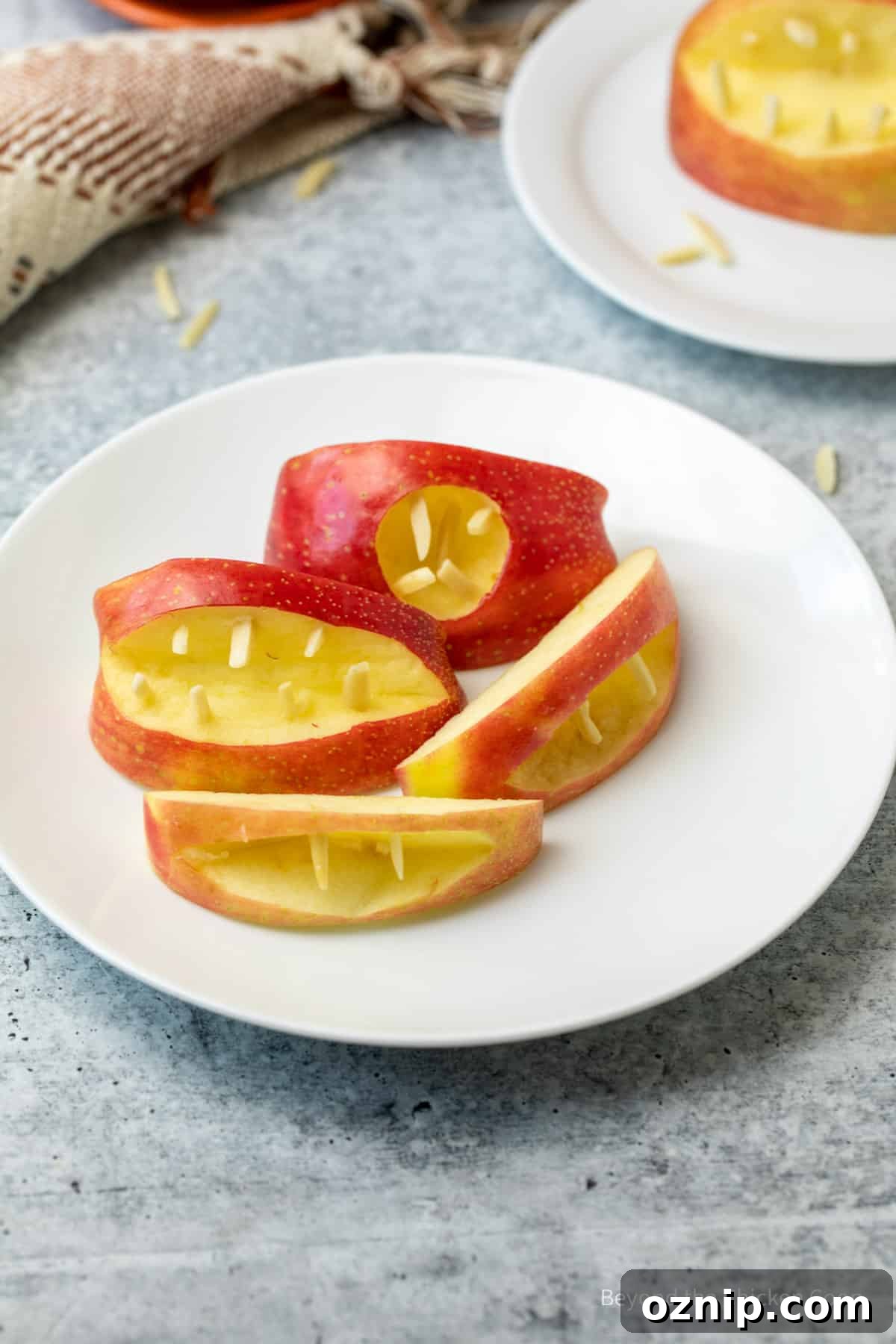 How to Make Apple Teeth for Halloween 4 A white plate filled with apple wedges shaped as mouths.