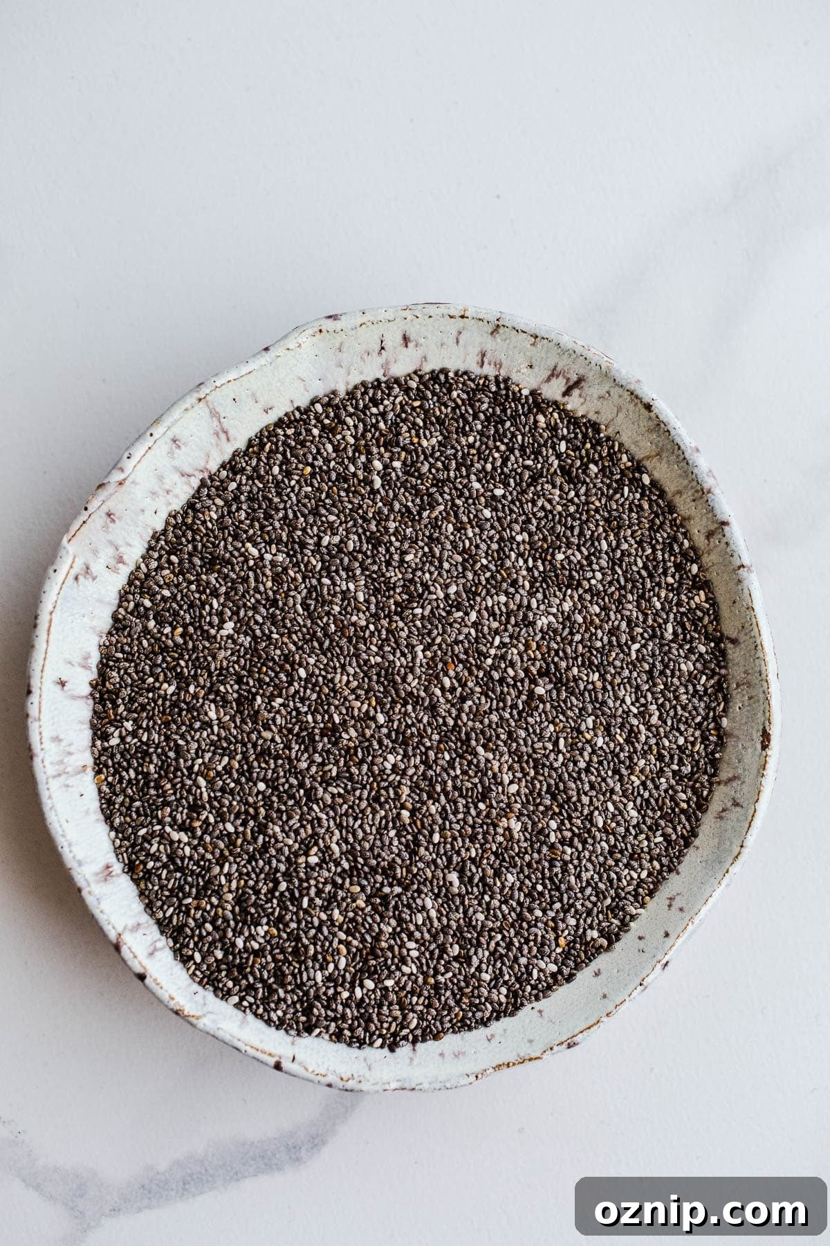 A small white bowl containing black chia seeds.