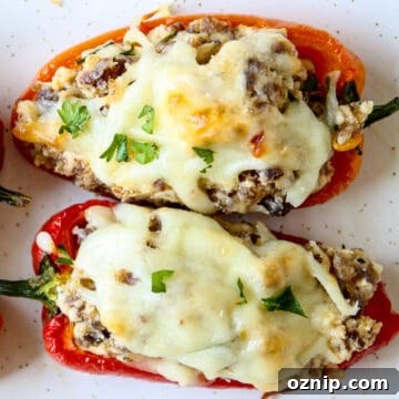 Sausage Stuffed Mini Peppers Recipe 9 Two sausage stuffed mini peppers on a white plate.