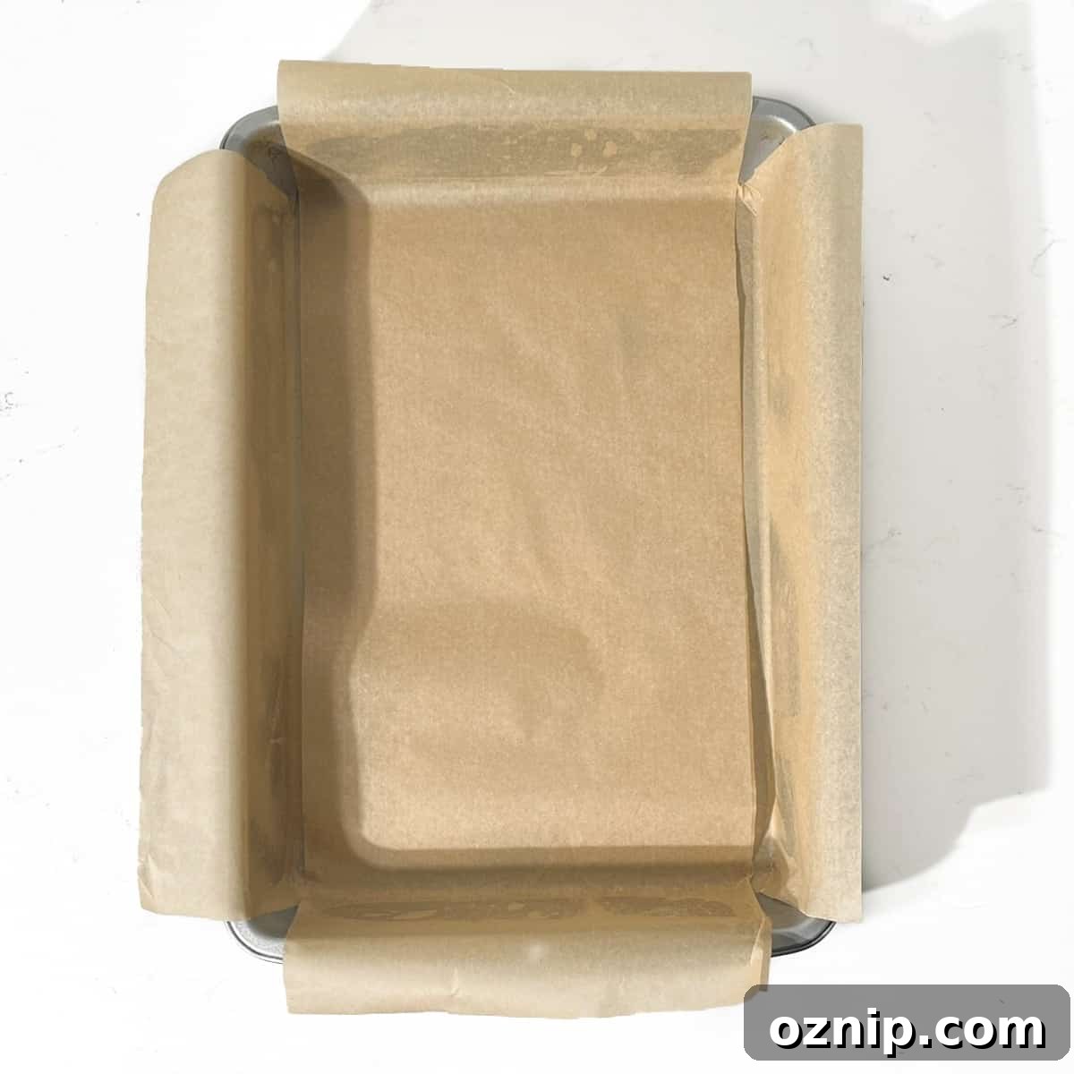 A baking tin prepared with a lining of baking paper. 