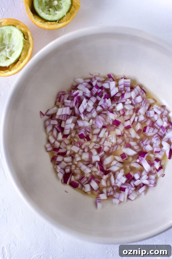 Small diced red onions in a bowl with lime and orange juices.