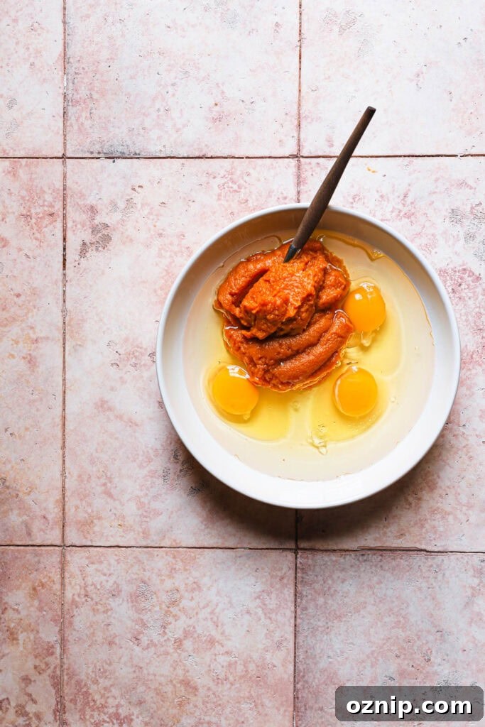 Moist Baked Pumpkin Donuts: Soft Fall Donut Recipe 3 A bowl with eggs and pumpkin puree with a fork.