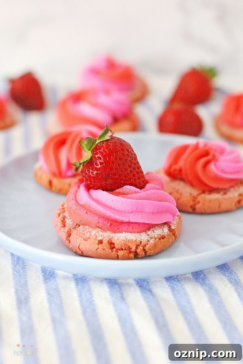 Image of strawberry cream cookies decorated with cream cheese frosting and fresh strawberries, on a serving plate