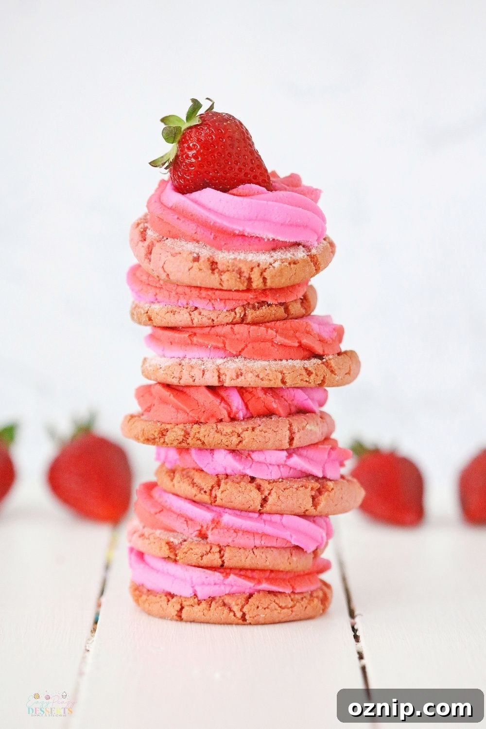 A stack of strawberry cream cheese cookies with a fresh strawberry on top