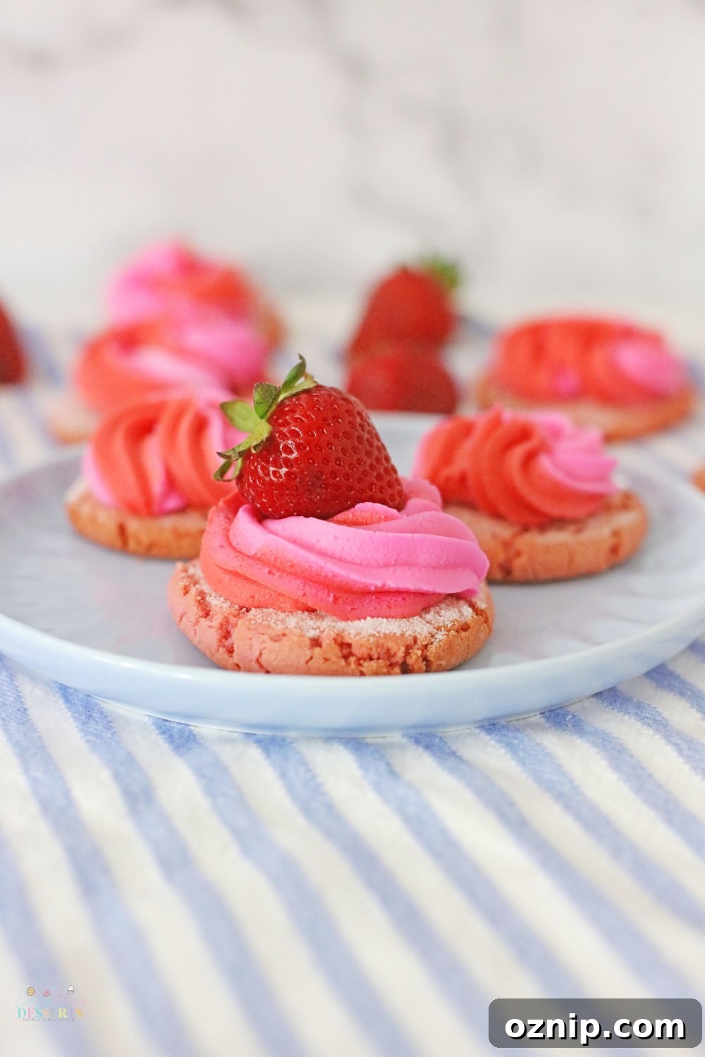 Close up image of strawberry cream cookies with fresh strawberry on top, on a serving plate